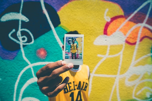 Portrait shot of a young man holding a picture of himself that blocks the view of his own faceholding a