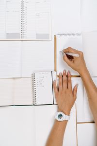 A table full of notebooks with a person writing in one