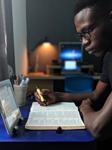 Man highlighting in a book and watching a video on a tablet