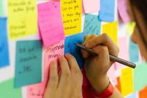 Person writing on wall of sticky notes