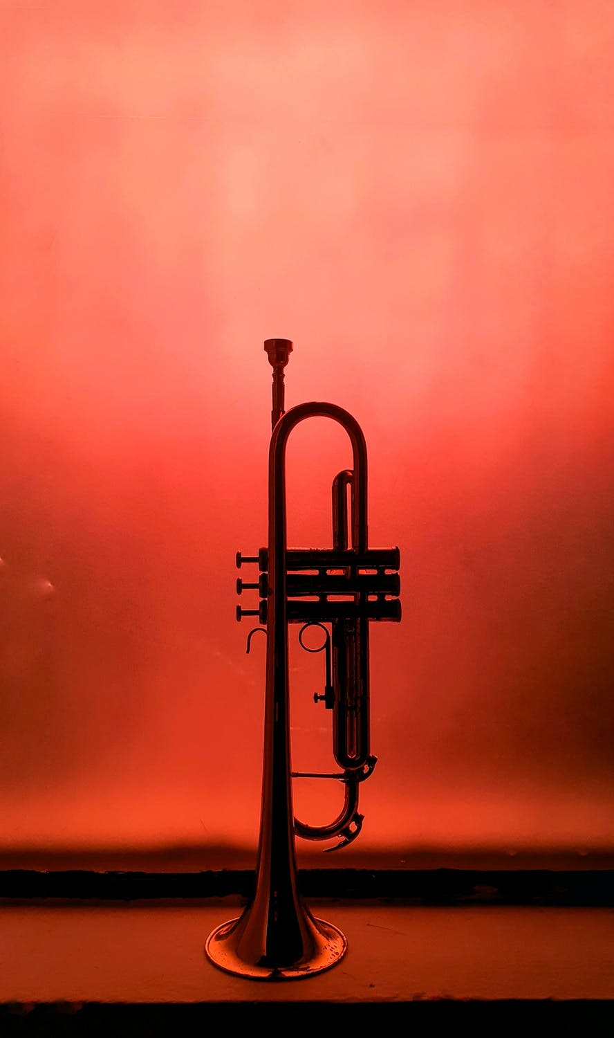 a trumpet sitting upright on water with an orange and punk background