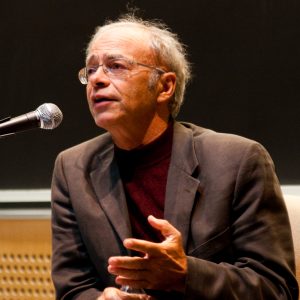 color photograph of a man (Peter Singer) speaking into a microphone