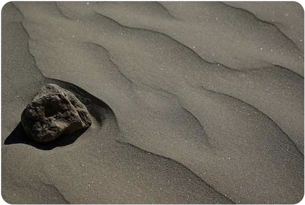 Figure 11. A craggy-textured rock is on the rippled sandy shore of a beach. Image is titled “Beach on the Chang Jiang (Yangtze)” by Eul Mulot (https://www.flickr. com/photos/mulot/3315444069) and is licensed under CC BY-NC-SA 2.0.