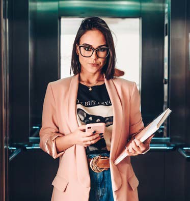 image of woman in an elevator with a phone and notebook in her hands