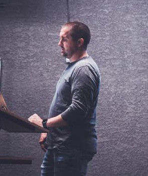 a man standing at a lectern looking down at his notes