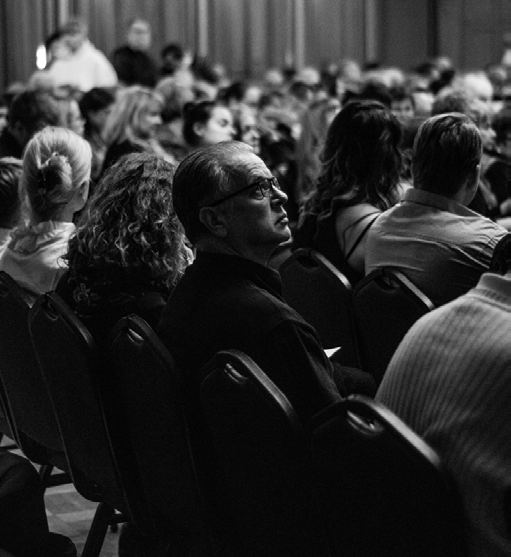 black and white image of an audience, with one member looking up
