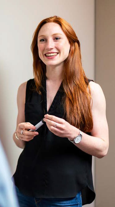 image of a woman holding a dry erase marker and smiling