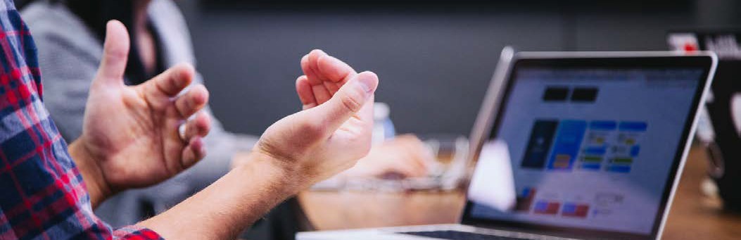 close-up image of a person's hands gesturing in front of a laptop