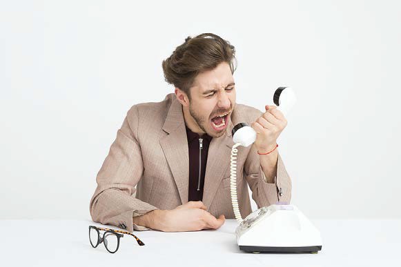 image of a man sitting in a white room yelling into a rotary phone