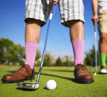 zoomed in image of golf ball and club with legs in the background