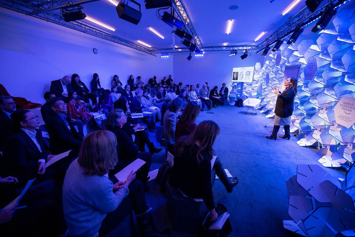 image of a woman standing in front of an audience with bright blue lighting