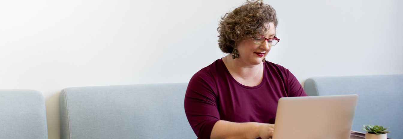 image of woman looking at and typing on a laptop