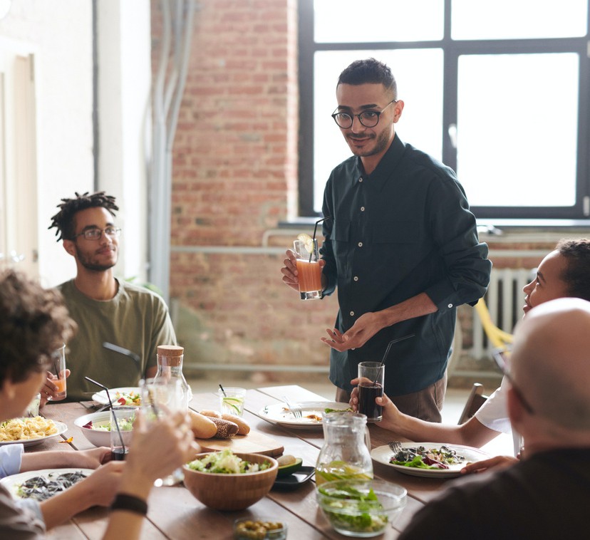 image of a man standing at the head of the table with a drink in his hand