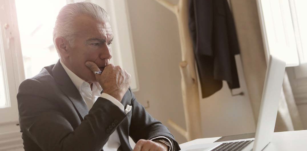 man wearing a suit staring intensely at a laptop screen