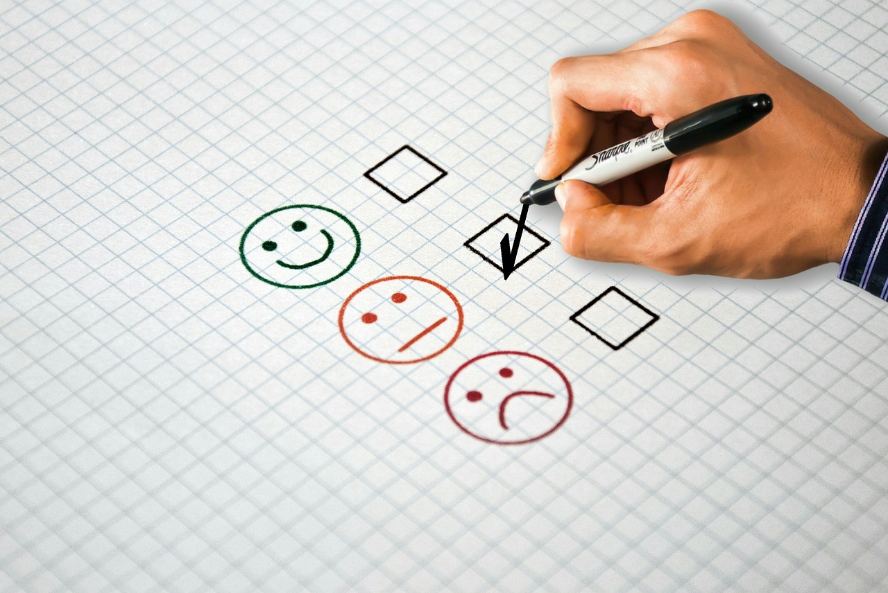 Survey of a smiley face, okay face, and sad face with a hand checking the bod for the okay face.