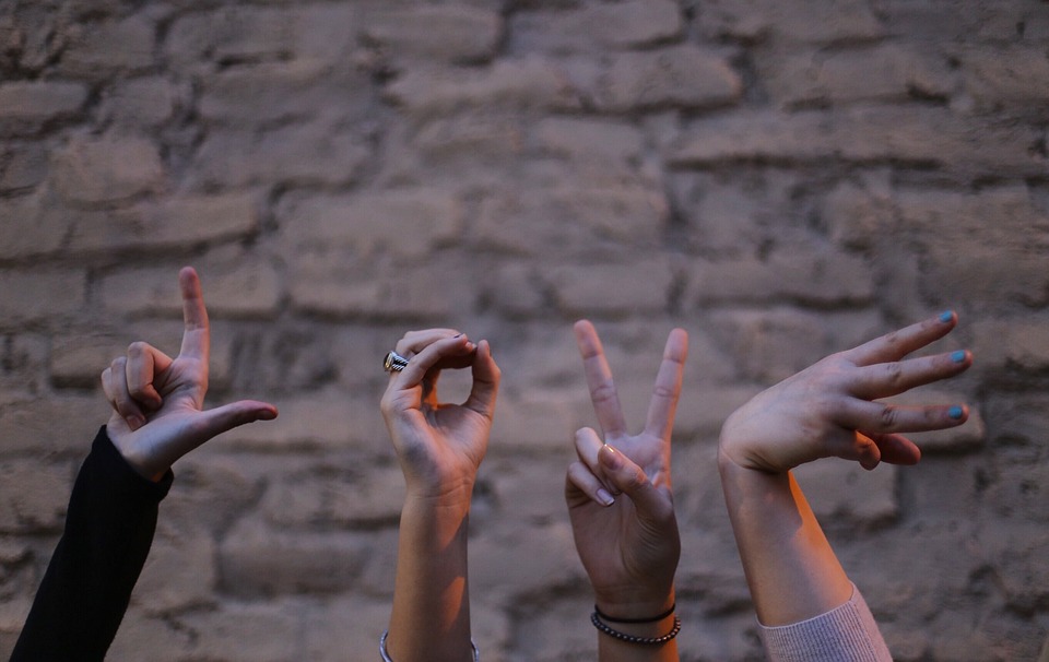 Four hands with different finger gestures.