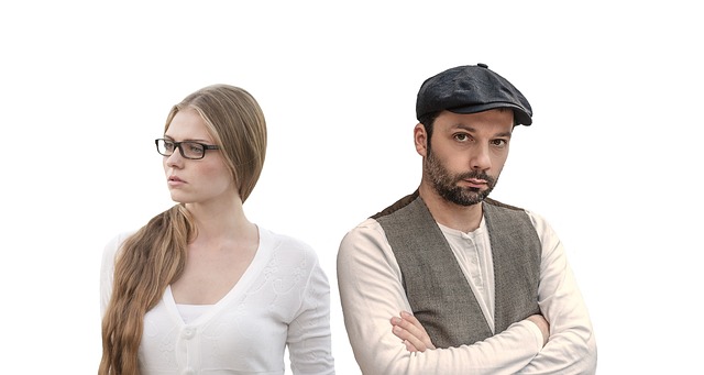 Woman with a frown is looking to the left while a man with crossed arms is looking to the right.