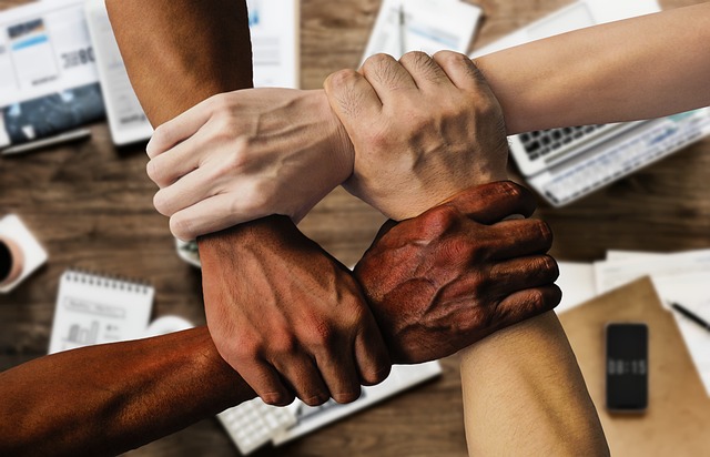 Hands of four diverse individuals linked.